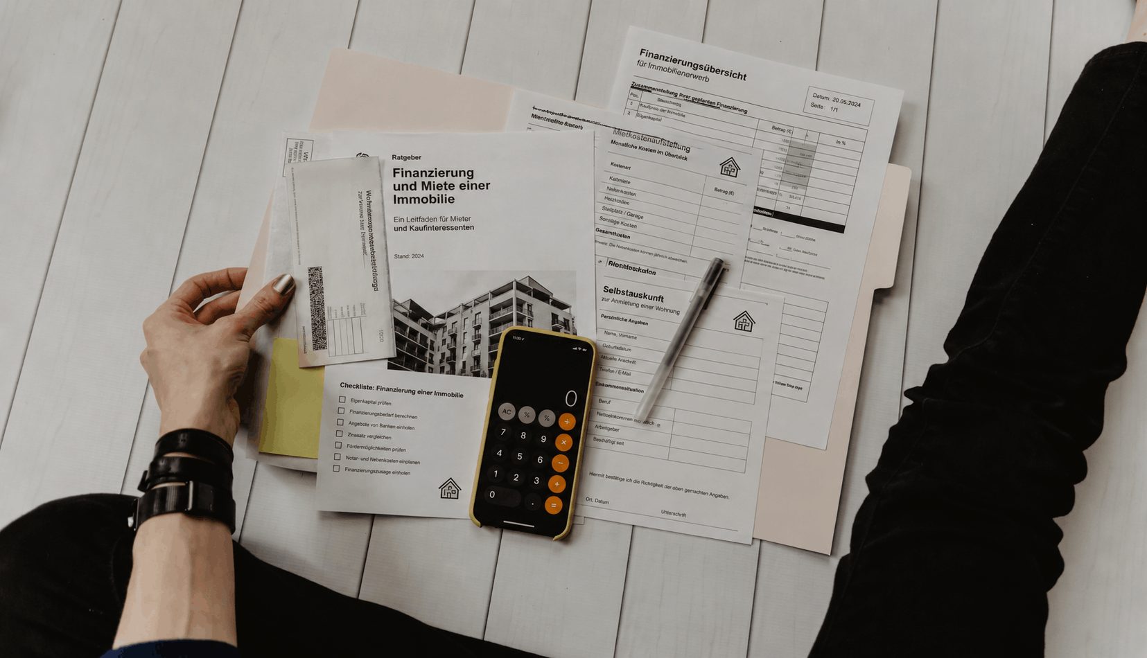 Finanzierungsunterlagen mit Checkliste und Taschenrechner auf einem Schreibtisch